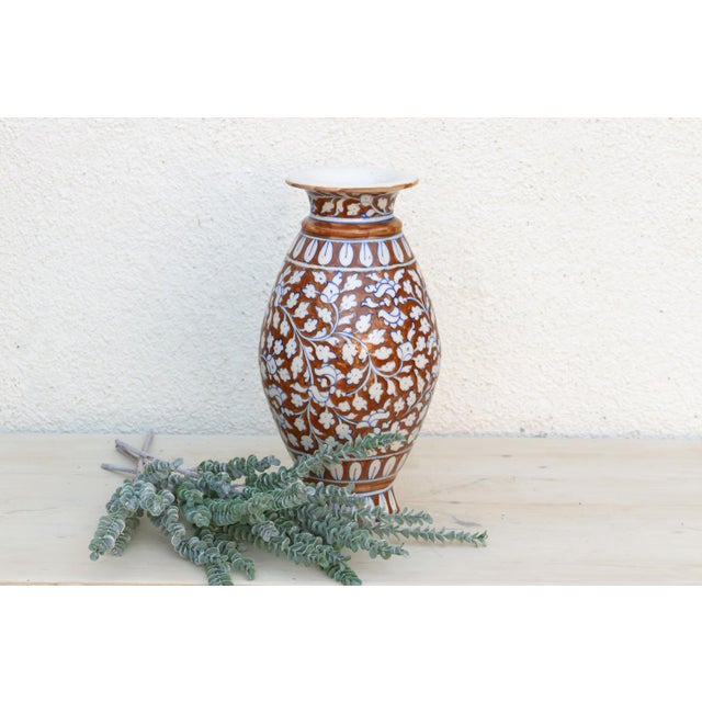 A tall, graceful baluster vase hand-painted in the rich, saturated palette Jaipur is known for: a deep rust-brown ground...