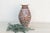 A tall, graceful baluster vase hand-painted in the rich, saturated palette Jaipur is known for: a deep rust-brown ground...