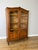 An elegant Vintage French Louis bookcase in oak, featuring glazed double doors, a shaped top, carved decorative details...