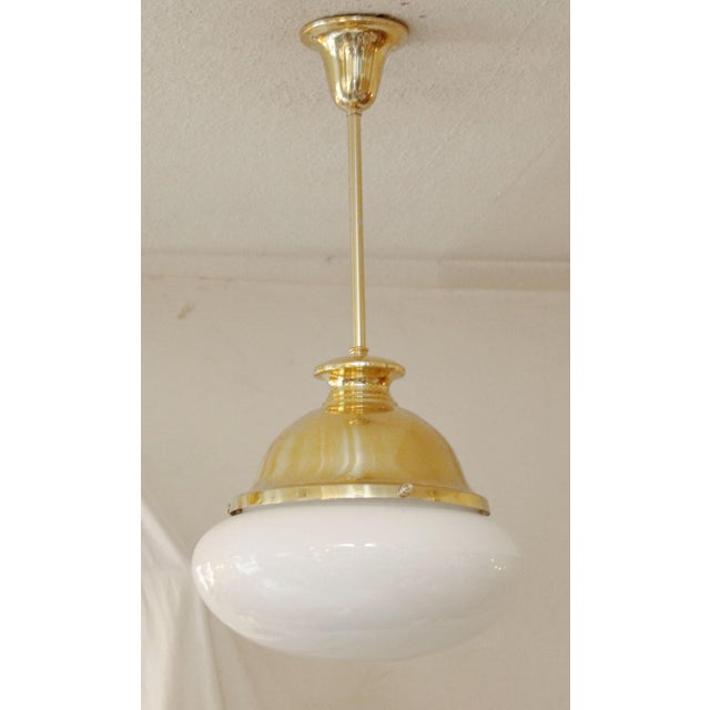 Art Deco pendant lamp, circa 1920. Dish-shaped body suspended from a brass tube. White opal glass shade. The lamp has been...