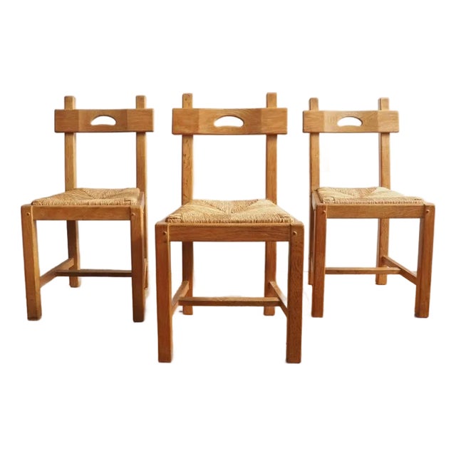 A sculptural set of six oak dining chairs with woven rush seats, crafted in France in the Brutalist style circa 1950.