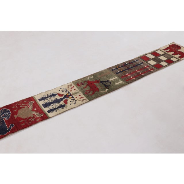 Hand-knotted in wool and originating circa 1950-1959, this 1x8 vintage Gabbeh pictorial extra-long runner is from...