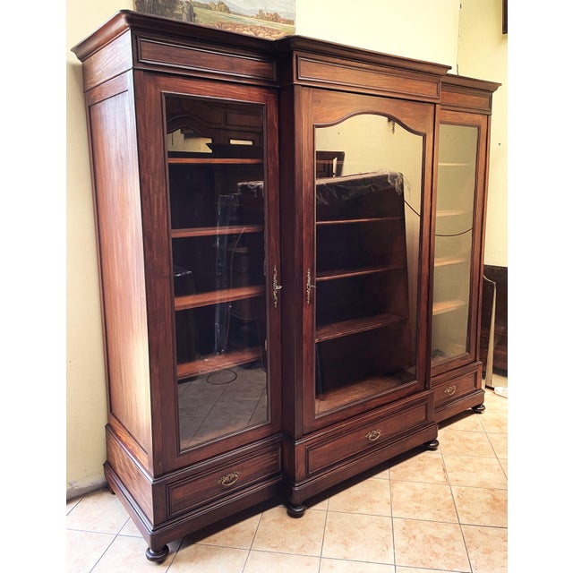 A bookcase/wardrobe dating to the turn of the 20th century, crafted in a late Historicist style with Neoclassical...