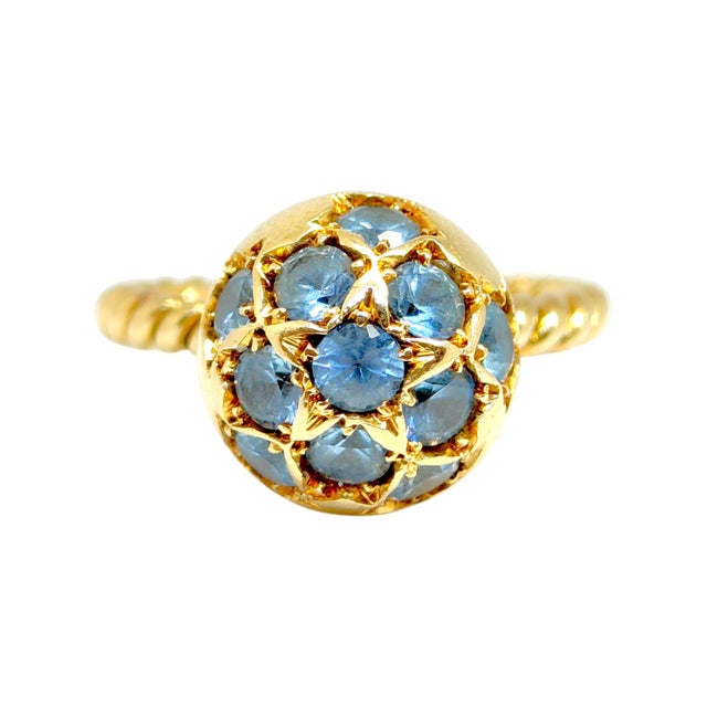 Vintage 18K yellow gold ring featuring and orb set with a cluster of blue zircons in star motif designs, supported by a...