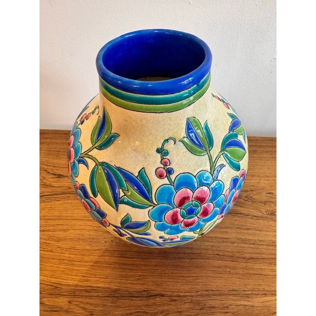 This vibrant Art Deco crackle-glazed ceramic vase features a bold floral pattern designed by Charles Catteau for Boch...