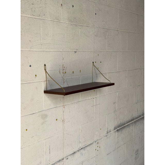 Elegant vintage Danish rosewood wall shelf featuring beautiful natural wood grain and minimalist brass-tone metal...