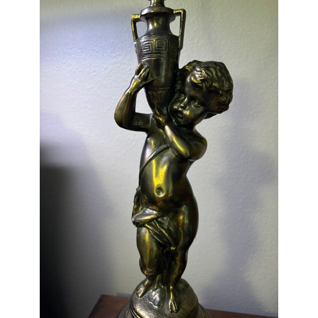 A beautifully detailed mid‑century brass lamp featuring a sculpted cherub standing atop a faceted cut‑glass base with a...