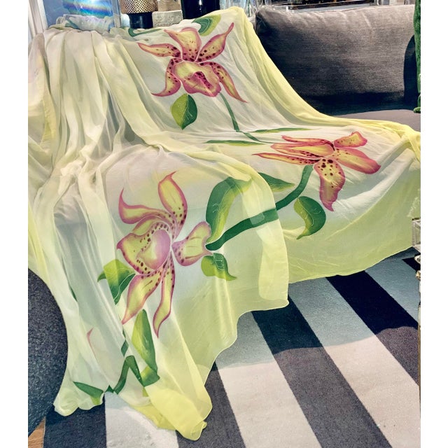This unique 100% silk throw is hand painted with large tropical orchid floral in tonalities of pink and green on a light...