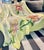This unique 100% silk throw is hand painted with large tropical orchid floral in tonalities of pink and green on a light...