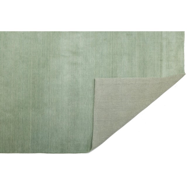 Discover our stunning handcrafted Gabbeh-style wool rug, showcasing a rich muted sage green design. Proudly part of our...
