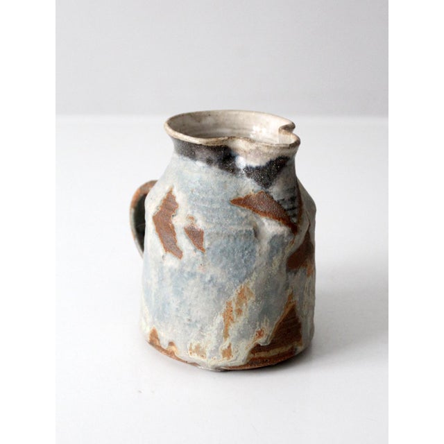 Vintage studio pottery pitcher with a sculptural, organically contoured form and a softly shaped pouring lip. The glaze...