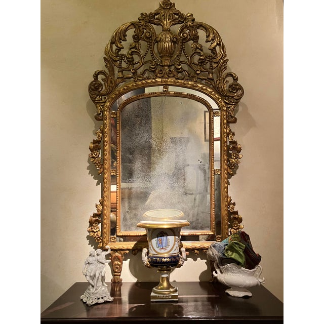 This antique 19th century french giltwood overmantel mirror, carved as a “marriage mirror” with foxed glass, was...
