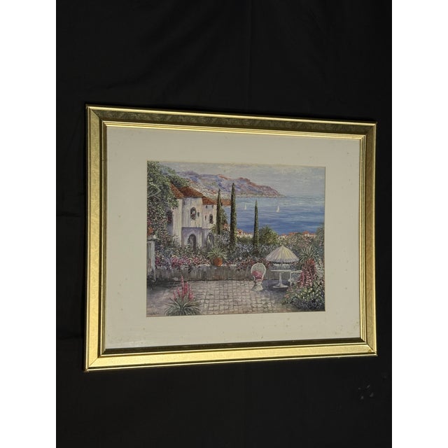 Elegant framed coastal landscape artwork featuring a seaside villa, garden patio, ocean view, mountains, and...