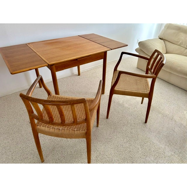 Classic Danish mid-century modern teak dining table with rounded corners and two (2) end-leaf folding extensions; two (2)...