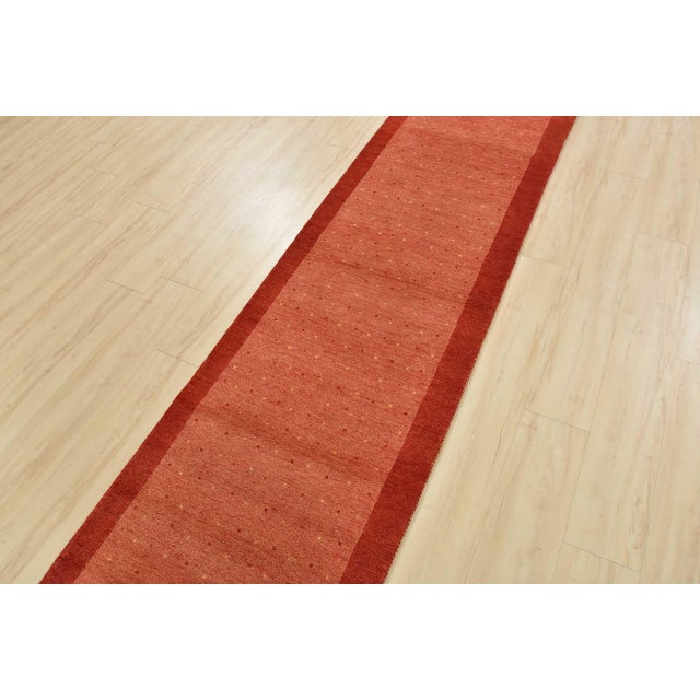 A contemporary Gabbeh runner hand-knotted with an all-wool pile on a cotton foundation. This oriental rug features an all-...