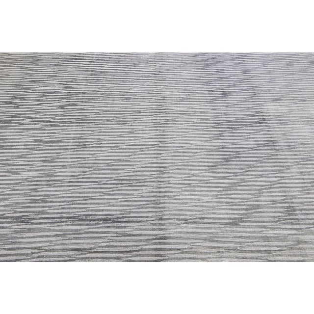 Meticulously crafted by hand using a blend of silk and wool, this exquisite contemporary rug showcases a stunning gray...