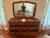A vintage solid cherry wood French Provincial style dresser featuring nine drawers in a serpentine configuration with...
