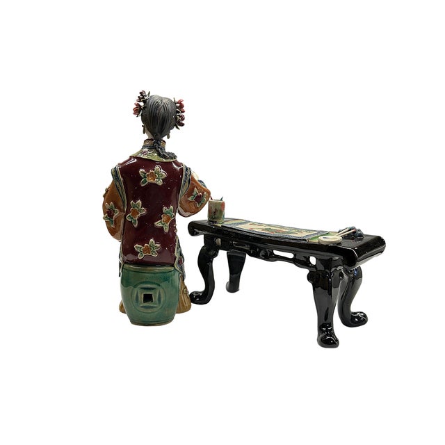 This stunning vintage porcelain figurine depicts a Chinese woman gracefully seated at a low table, capturing a moment of...