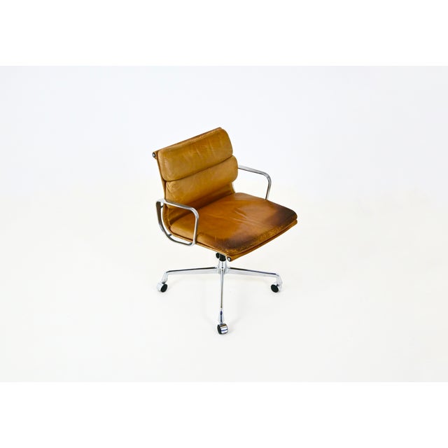 Brown leather armchair with aluminum base and wheels. Stamped Herman Miller. Wear consistent with age and use. This piece...