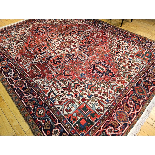 "This vibrant vintage Persian Heriz rug, crafted in the first quarter of the 20th century, presents a rich brick red field...