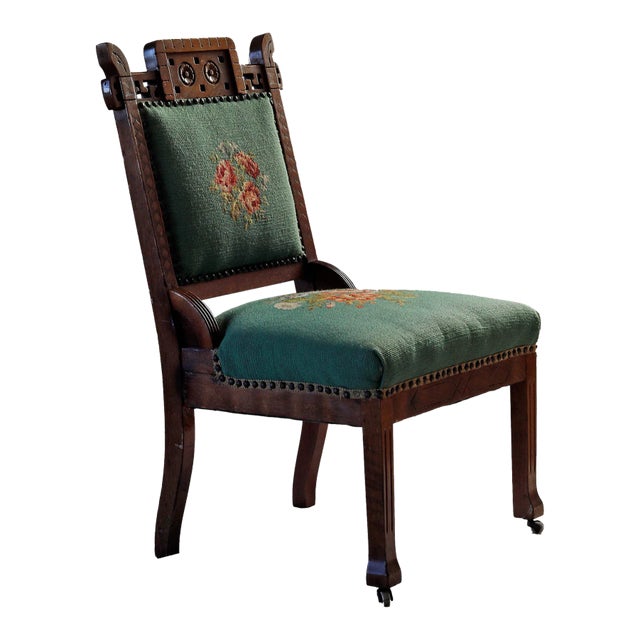 Antique Aesthetic Movement chair with needlepoint upholstered seat and backrest and hand carved detail. Casters on front...
