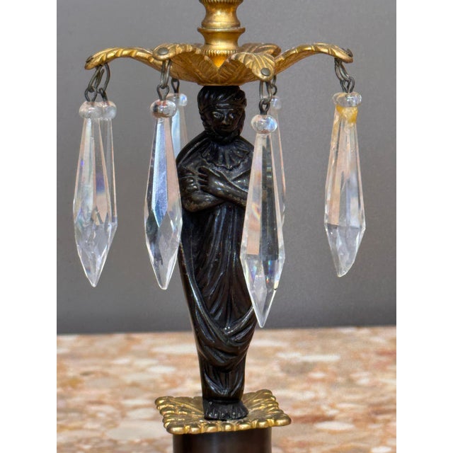 A finely detailed pair of figural girandoles in ormolu and patinated bronze, each modeled as a classical draped figure...