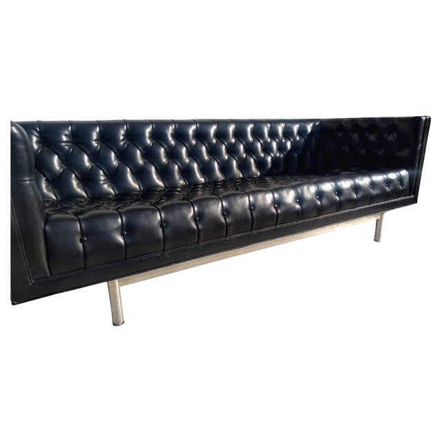 A gorgeous and large mid-century modern sofa. This beautifully tufted Black faux leather sofa with a chrome base was...