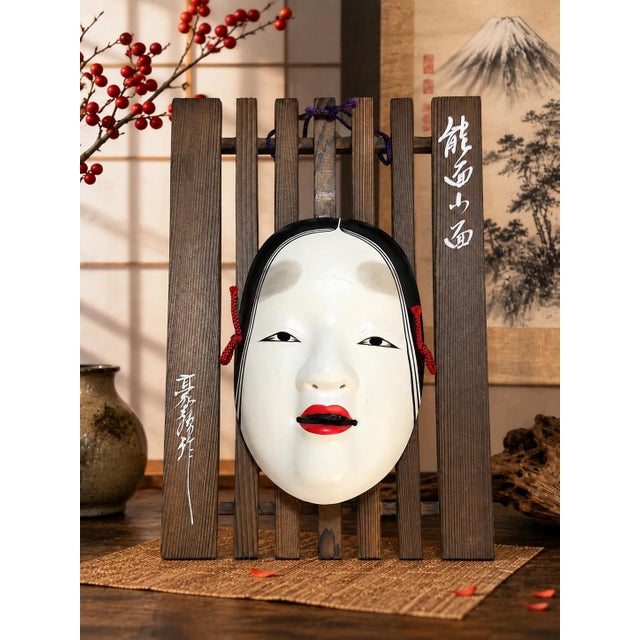 A striking vintage Japanese Ko-omote Noh mask presented on its original slatted wood wall display. Ko-omote (小面),...