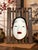A striking vintage Japanese Ko-omote Noh mask presented on its original slatted wood wall display. Ko-omote (小面),...