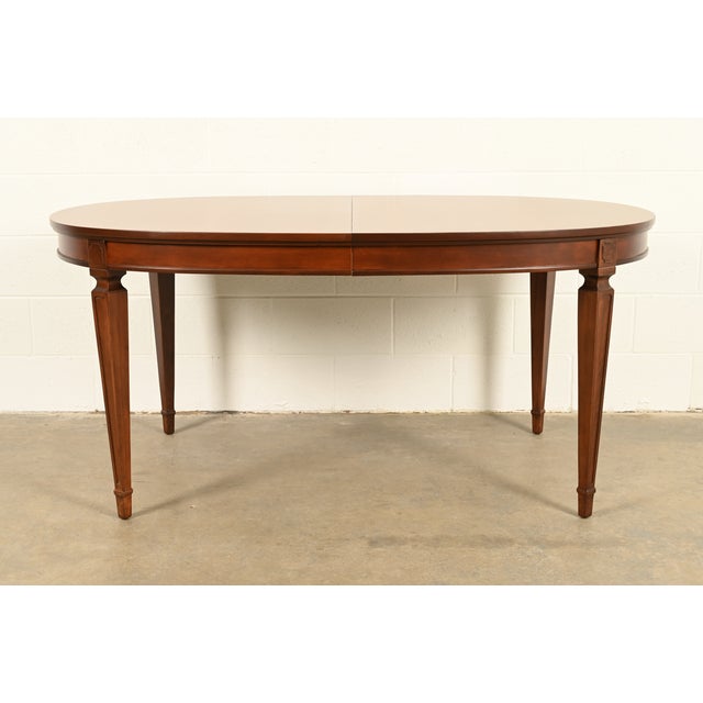 A gorgeous French Regency Louis XVI style carved cherry wood extension dining table By Drexel USA, Circa 1960s Measures:...