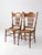 Pair of antique Victorian pressed-back cane chairs featuring ornate floral carvings, decorative scrollwork, turned spindle...