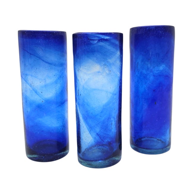 A trio of deep cobalt vessels—hand-blown, bold, and beautifully imperfect. Each carries with it the hush of molten memory,...
