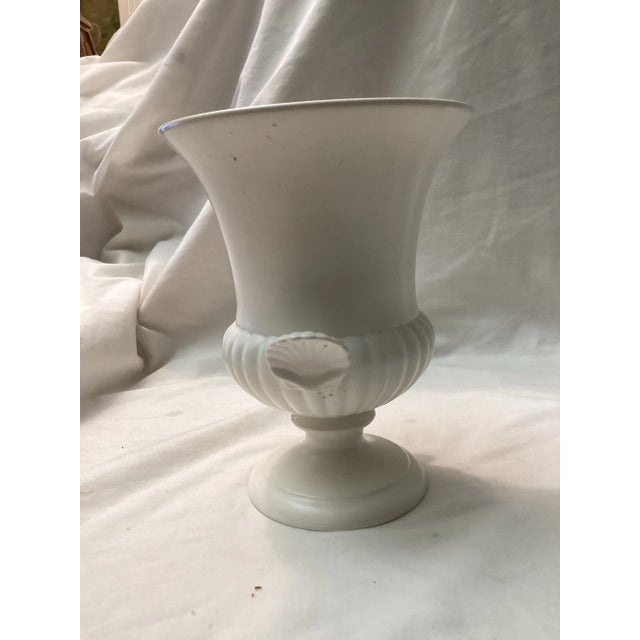 Elegant Wedgewood, pedestal urn vase featuring a flared rim, ribbed lower body, and applied shell handles. Finished in a...