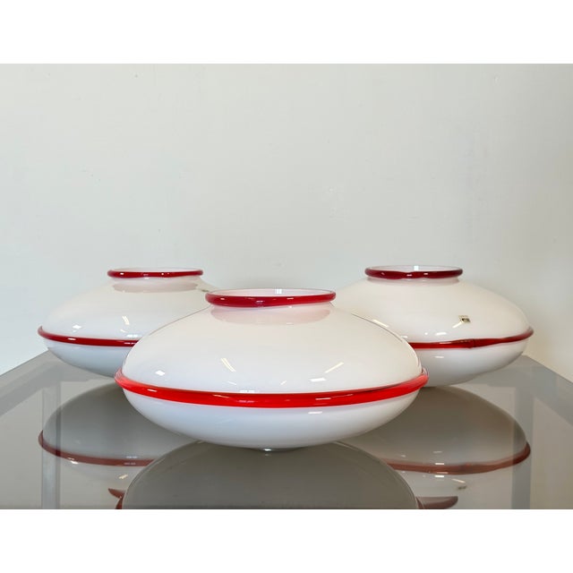 Three 70s Murano glass ceiling lights by Fratelli Toso, white glass diffuser with red profile This piece has an...