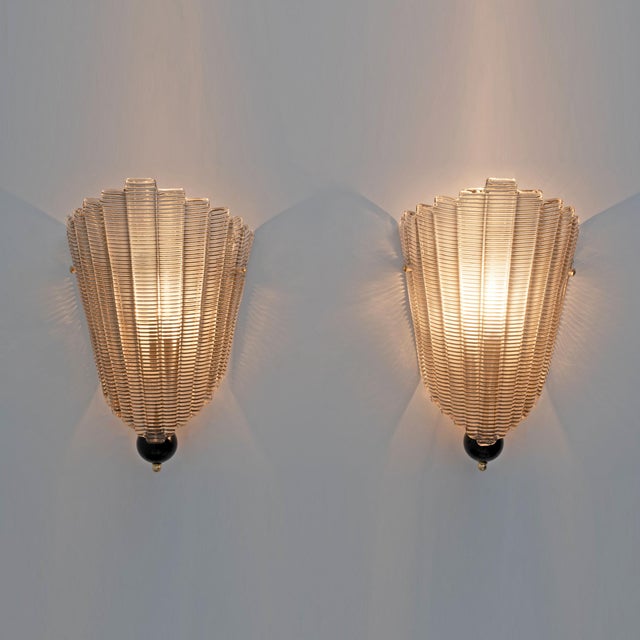 A pair of textured murano glass wall sconces. The fluted and curved glass creates a striking decorative effect, completely...