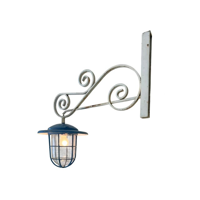 Charming vintage wall light featuring a beautifully crafted wrought iron bracket combined with a lantern lamp with a cage...