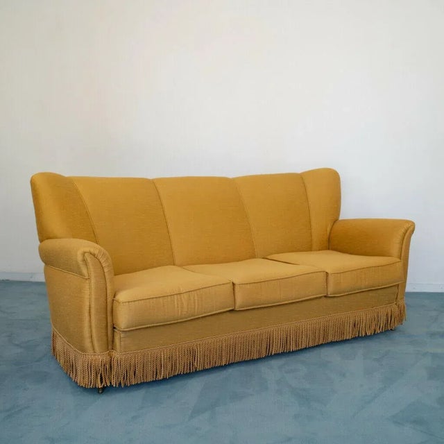 3 seater sofa and 2 armchairs. Patented by Isa famous company. Structure wood, brass feet and fabric mustard color. The...