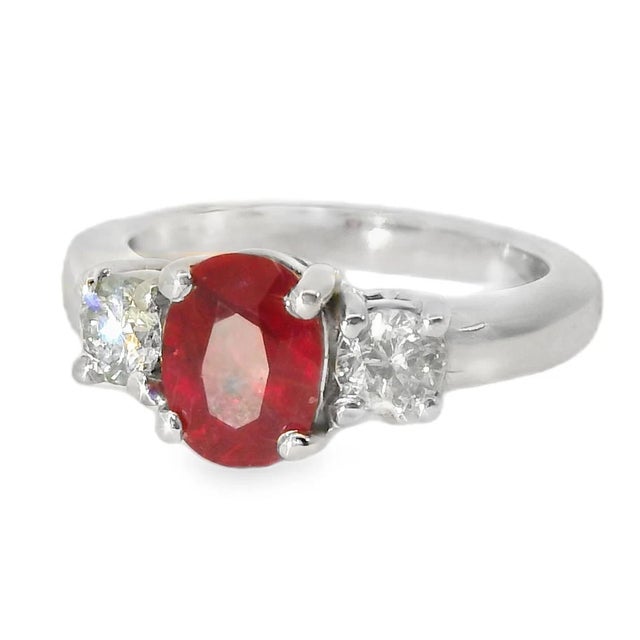 14K White Gold Ruby Diamond Three-Stone Ring This elegant estate ring features a natural ruby center stone measuring 10 mm...