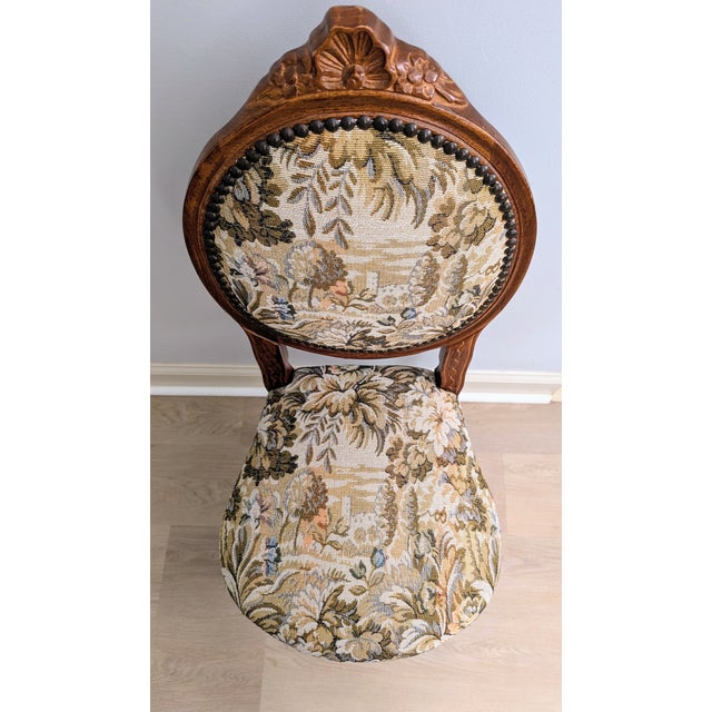 This gorgeous vintage chair has a carved walnut frame with tapestry upholstery and nail head trim on back and around seat....