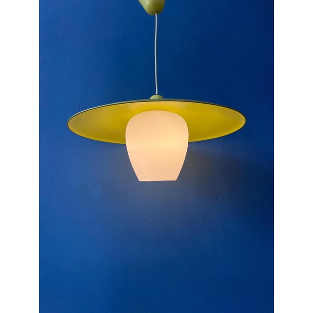 Yellow UFO mid-century pendant lamp featuring a beautiful opaline glass inner shade and a yellow metal outer shade. The...