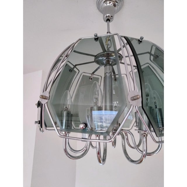 This striking mid-century modern chandelier from the 1970s features a sophisticated blend of chrome-plated metal and...
