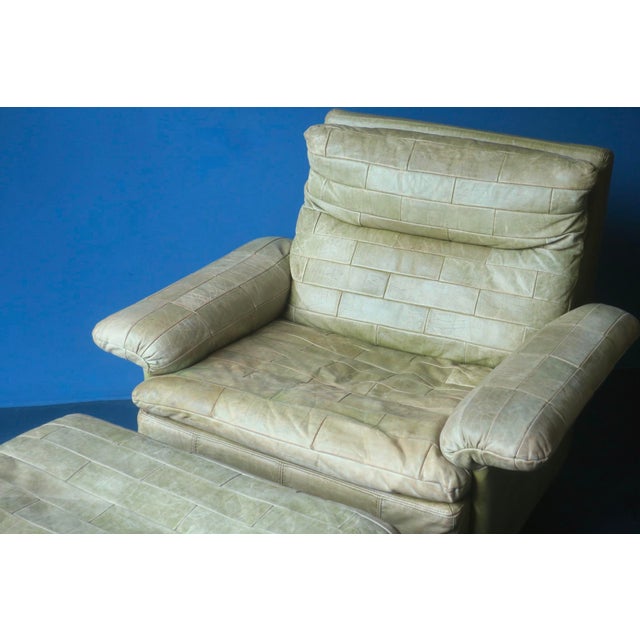 Patchwork leather lounge chair with ottoman in olive green dating from about 1970. High quality piece from the German...