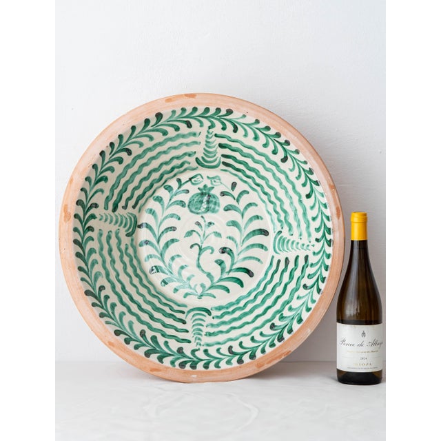 A large hand-painted Spanish ceramic wall bowl from Granada, decorated with the green pomegranate that is the city's own...