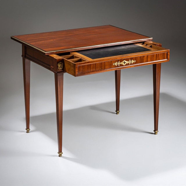 An elegant Neoclassical desk featuring one drawer and a sliding tabletop. The piece is beautifully veneered and hand-...