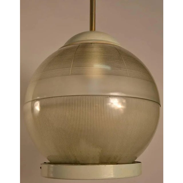 Spherical form Holophane shade hangs from brass tube. Capable of high wattage generating high light if desired. Metal cap,...