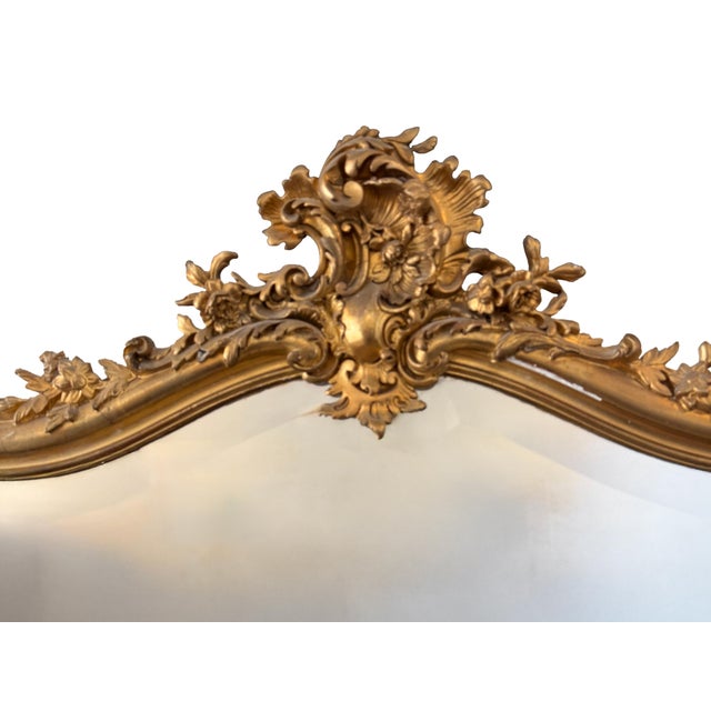 Elegant French Louis XV style giltwood mirror featuring an ornate Rococo-inspired frame with richly carved floral and...