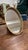 An ornate vintage oval tabletop vanity mirror featuring a detailed, pierced filigree gilt-metal rim. Designed with an...