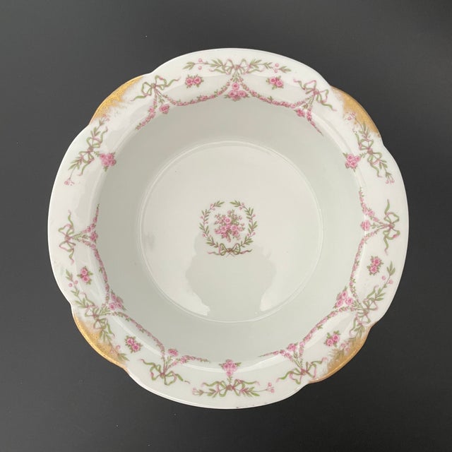 An antique Charles Ahrenfeldt soufflé dish in the AHR735 pattern, featuring a wreath motif at the center with pink rose...