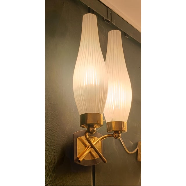 A pair of wall lights dating from around 1950, featuring double arms, polished brass brackets with a wall-mounted frame...