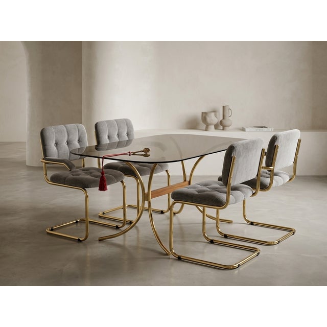 This sophisticated dining set features a stunning combination of brushed brass frames and premium gray velvet upholstery....